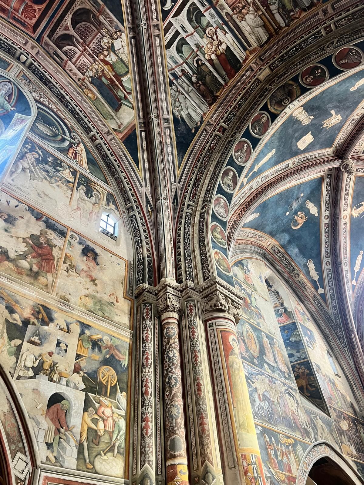 Ein detaillierter Blick in das Innere einer Kirche, mit aufwendigen Säulen und Fresken, die religiöse Szenen darstellen.
