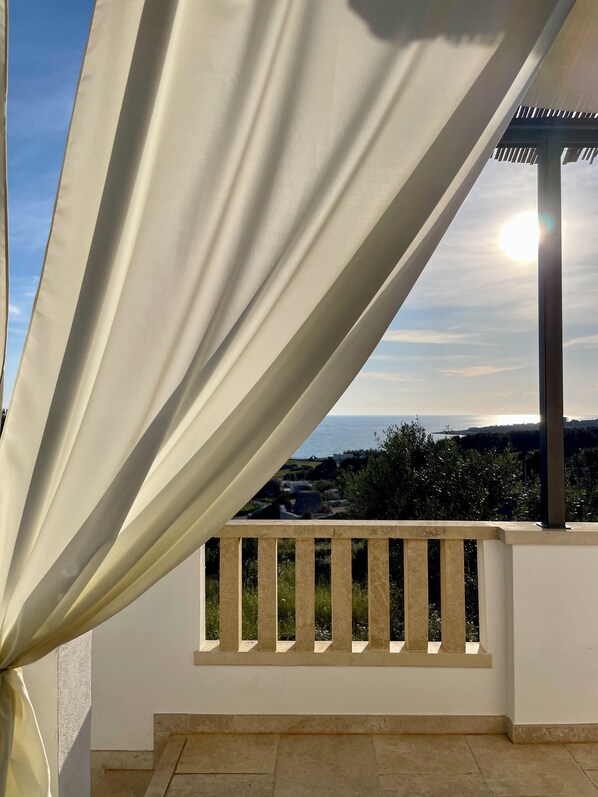 A balcony with a view of the sea and a pergola structure.