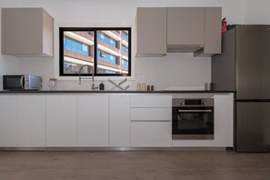 A modern kitchen with white cabinets, a stainless steel refrigerator, a microwave, and an oven. - City Center Modern Boho Stay (Nicosia)