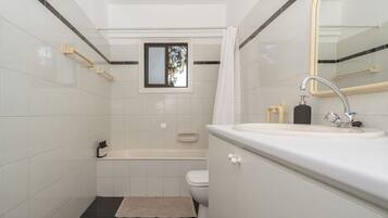 Badkamer | Een bad/douchecombinatie, een haardroger, handdoeken, zeep