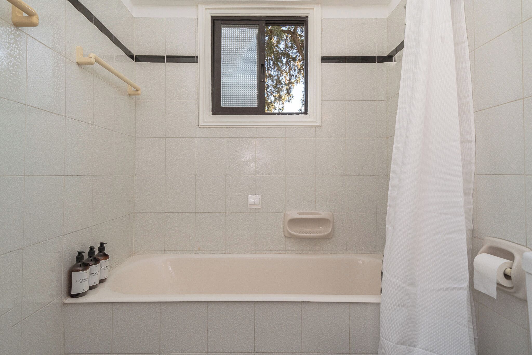 Un baño con bañera, ventana y cortina de ducha.