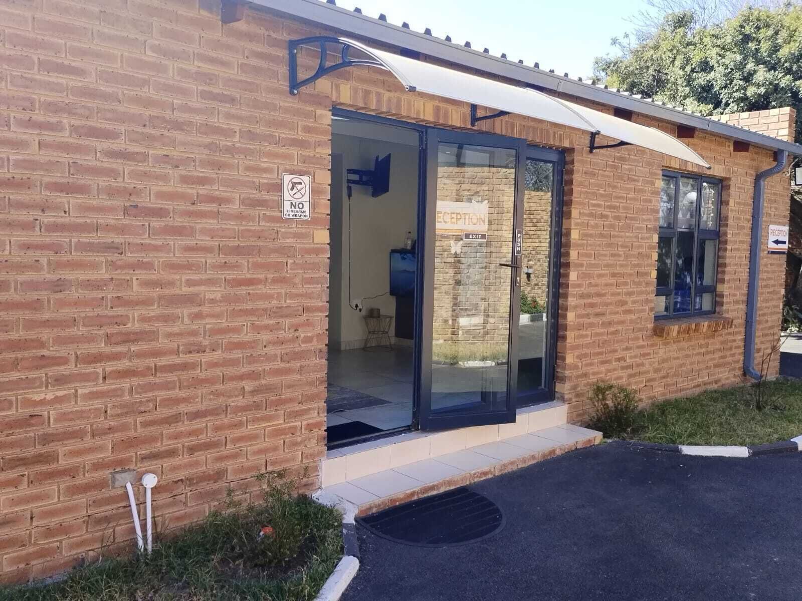 A brick building with a reception area, glass doors, and a sign indicating no firearms or weapons allowed.