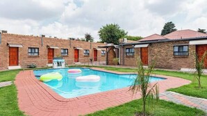 Ein Innenhof mit Schwimmbad, Backsteingebäuden und einem kleinen Garten.