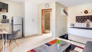 Ein kompaktes Hotelzimmer mit Küchenzeile, einem Bett, einer Essecke und einem Badezimmer.
