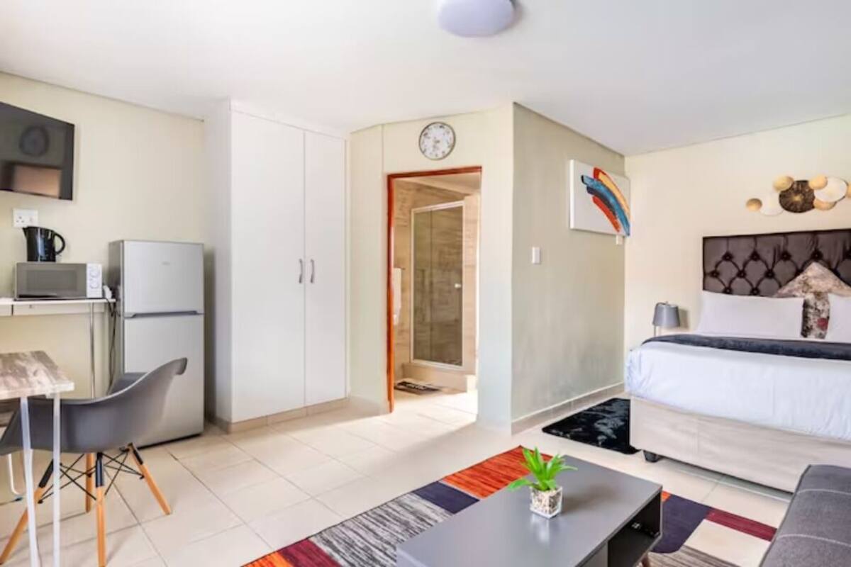 Ein kompaktes Hotelzimmer mit Küchenzeile, einem Bett, einer Essecke und einem Badezimmer.