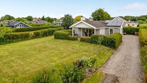 A residential area with houses, a well-maintained lawn, and a gravel path.
