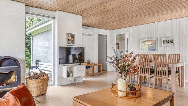 A modern living room with a fireplace, a TV, and a dining area with wooden furniture.