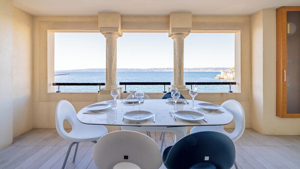 A dining area with a table set for four, large windows with a view of the sea, and a balcony with a railing. - Luxury and sea view, 3 bedrooms, plage des Catalans (Marseille)