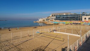A beach volleyball court with a net, adjacent to a building with multiple balconies overlooking the beach. - Luxury and sea view, 3 bedrooms, plage des Catalans (Marseille)