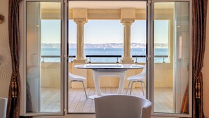 A balcony with a table and chairs, offering a view of the sea and distant mountains. - Luxury and sea view, 3 bedrooms, plage des Catalans (Marseille)