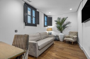 Un salon moderne avec un canapé, un fauteuil à motifs et une plante en pot.