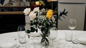 A dining table set with white plates, cutlery, and clear glassware, accompanied by a vase of white and yellow roses. - Principe Genoa Home Train Station Piazza Principe (Unknown)