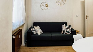 A modern living room with a black sofa, a round table, and decorative wall art. - Principe Genoa Home Train Station Piazza Principe (Unknown)