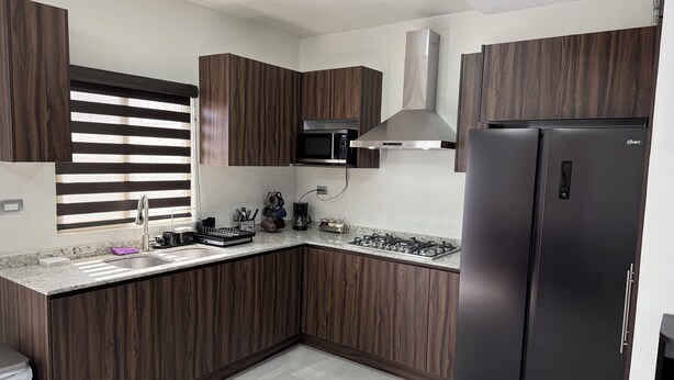 Eine moderne Küche mit dunklen Holdekor-Schränken, einem Edelstahl-Kühlschrank und einem Gasherd.
