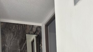 Un couloir avec un mur en marbre, un tabouret en bois et une main courante noire.