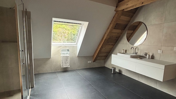 Een moderne badkamer met dakraam, grote spiegel en minimalistisch design.