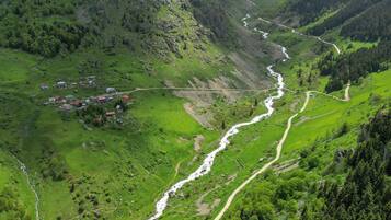 A mountainous landscape with a river, green valleys, and scattered buildings.