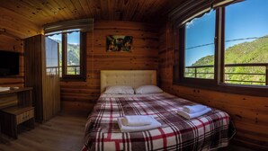 Una habitación de cabaña de madera con una cama, un televisor y un cuadro en la pared.