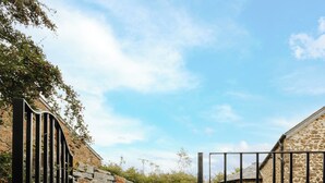 A stone staircase leading to a gated entrance with a clear sky above.