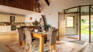 A spacious kitchen with wooden cabinets, a dining table with chairs, and a large window.