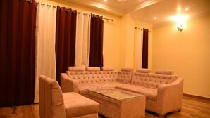 A living room with a large beige sectional sofa, two armchairs, and a glass coffee table.