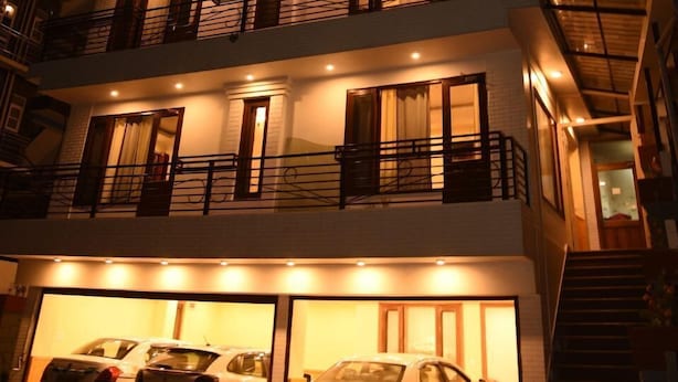 A multi-story building with two visible garage doors, each housing a car.