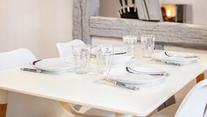 Een nette, moderne eetruimte met witte tafels en stoelen, helder glaswerk en een minimalistische inrichting.