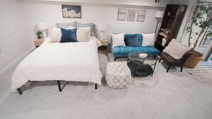 Een slaapkamer met een groot bed, een bank, een stoel en een bijzettafeltje.