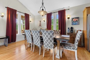 Un comedor con una mesa de madera, sillas estampadas y una araña.
