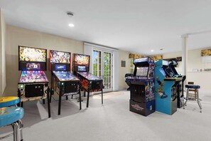 Habitación con máquinas de videojuegos, una silla azul y una puerta que da al exterior.
