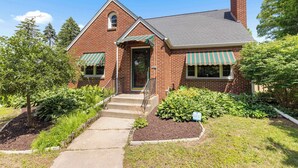A brick building with a green door, a small porch, and a window with a green awning. - Your friendly neighborhood Airbnb (Rockford)