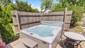 A hot tub with a control panel, a small table, and a chair on a wooden deck. - Your friendly neighborhood Airbnb (Rockford)