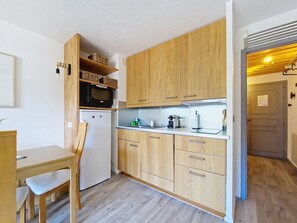 A compact kitchen with wooden cabinets, a white refrigerator, and a microwave on the countertop. - TOVASSIERE TS113 NATURE & VIEW 4 Pers. (Châtel)