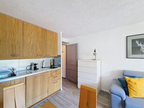 A modern kitchen with wooden cabinets, a white countertop, and a small sink. - TOVASSIERE TS113 NATURE & VIEW 4 Pers. (Châtel)