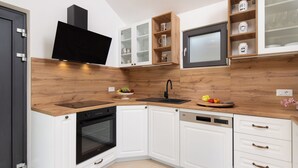 Eine moderne Küche mit weißen Schränken, einem schwarzen Backofen, einer Spülmaschine und einer Holz Arbeitsplatte.
