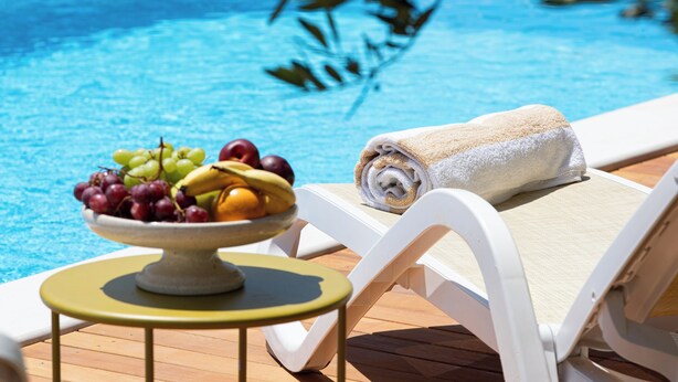 Ein Poolbereich mit Obstschale, Handtuch und Liegestuhl.