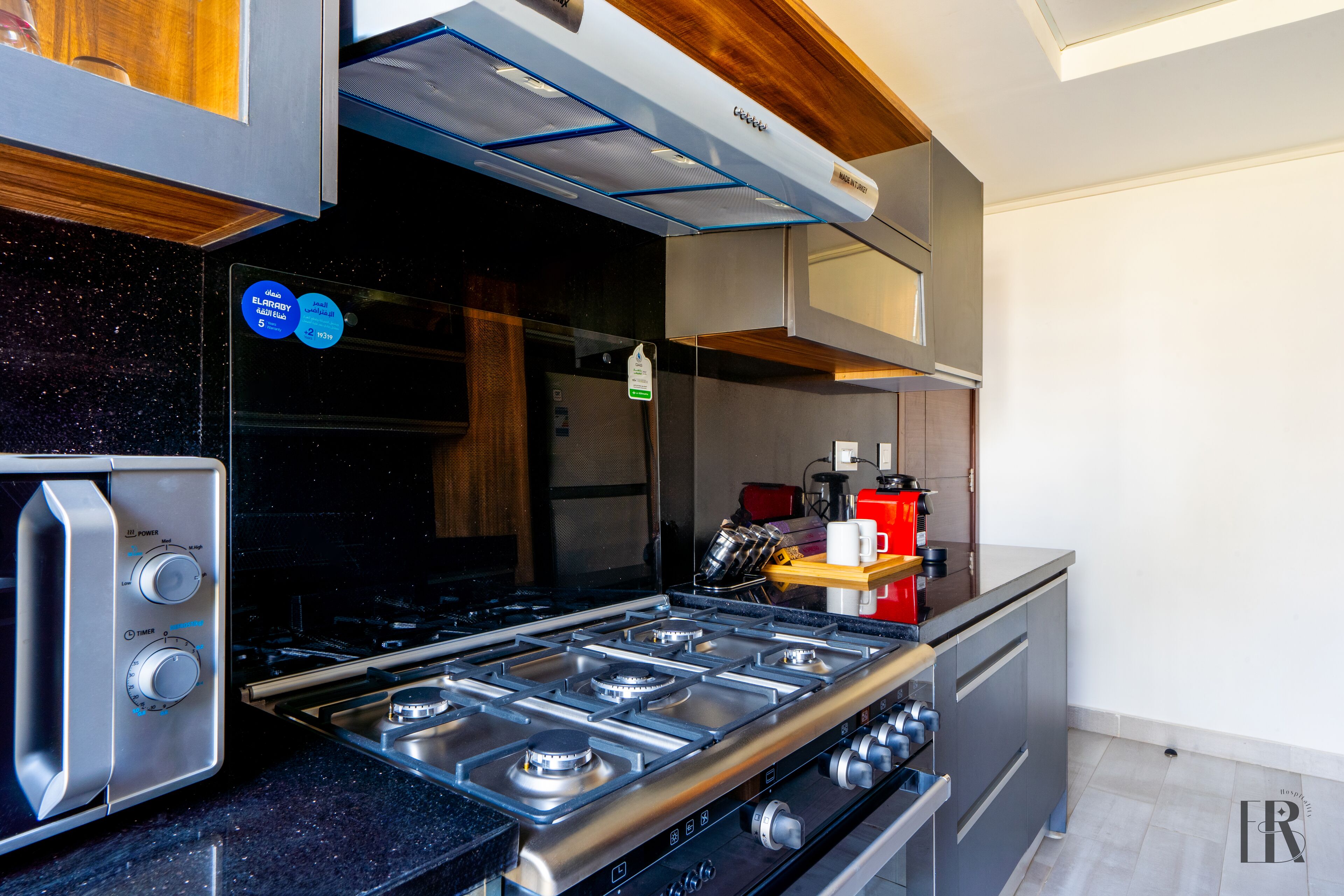 Une cuisine moderne équipée d’une cuisinière à gaz, d’un four encastré et d’une machine à café.