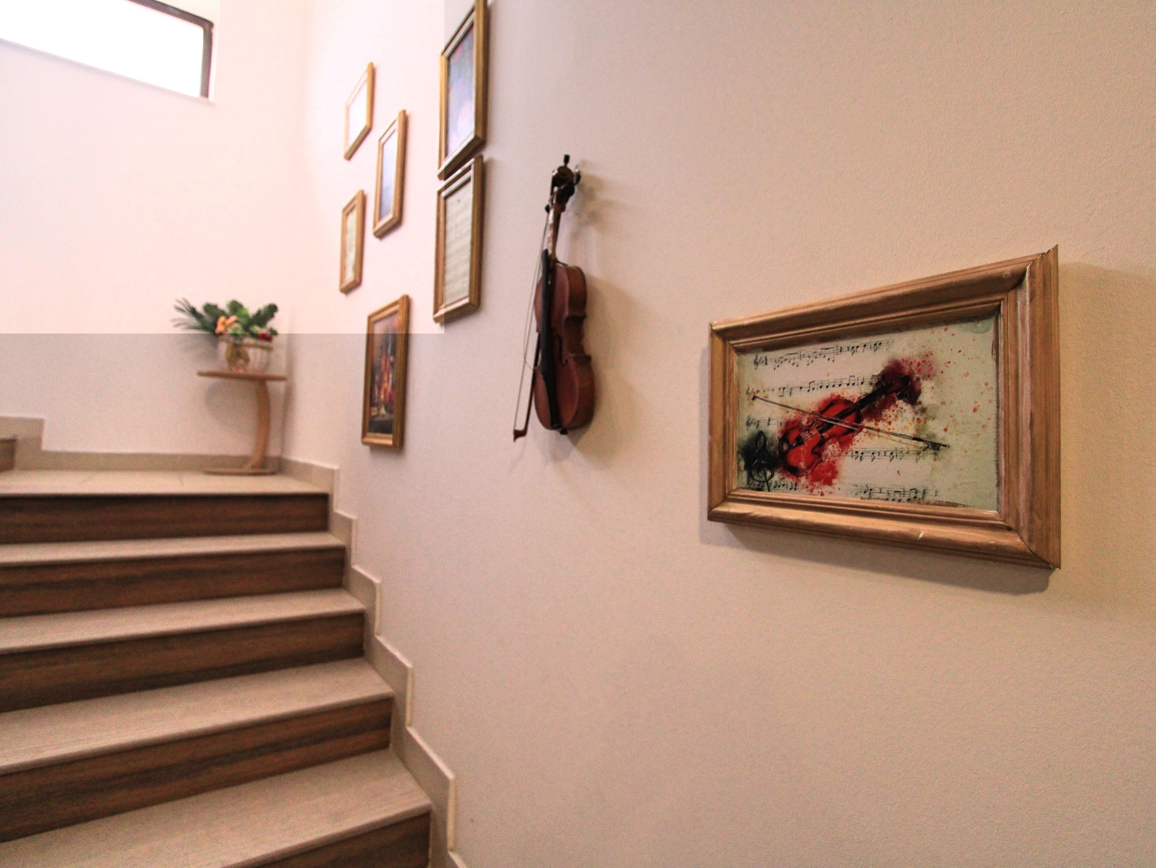 A staircase with wooden steps leading upwards, flanked by framed artworks on the walls.