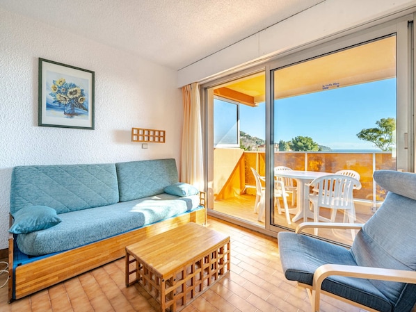 Ein Wohnzimmer mit Sofa, Couchtisch und Blick ins Freie.