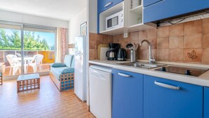 Cocina compacta con armarios azules, un microondas, una cafetera y un lavabo.