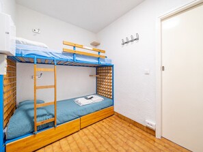 A bunk bed room with a wooden ladder, a blue mattress, and a small shelf.