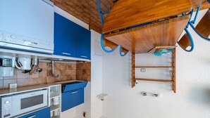 A kitchen with blue cabinets, a wooden ceiling, and a built-in microwave. - Apartment for 6, terrace, Wi-Fi included (Roquebrune-Cap-Martin)
