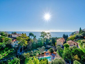 A coastal property with a swimming pool, terraced gardens, and ocean views.