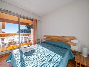 A bedroom with a bed, a wooden headboard, a bedside table, and a view of an outdoor balcony with a table and chairs. - Apartment 6 pers, sea view, Wi-Fi, Roquebrune-Cap-Martin (Roquebrune-Cap-Martin)