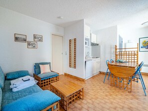 A compact living space with a sofa, a small dining table, and a kitchen area.