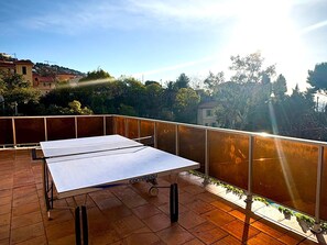 A ping pong table on a balcony with a view of trees and buildings. - Studio for 4 with unlimited Wi-Fi, sea view from the terrace (Roquebrune-Cap-Martin)