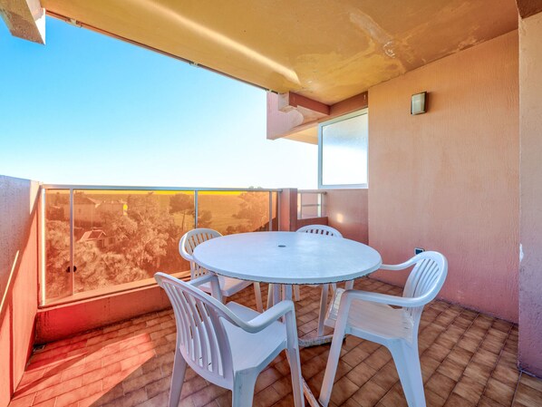 Un balcon avec une table ronde et quatre chaises, donnant sur un quartier résidentiel.