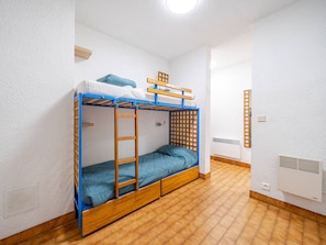 Et soveværelse med køjeseng, stige, lille hylde og et vindue.