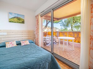 A bedroom with a large sliding glass door leading to an outdoor patio area with a table and chairs. - Apartment 8 pers., sea view, Wi-Fi, 1 bedroom (Roquebrune-Cap-Martin)