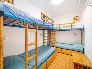 A dormitory room with bunk beds, a small wooden table, and a window with a wooden lattice. - Apartment 8 pers., sea view, Wi-Fi, 1 bedroom (Roquebrune-Cap-Martin)